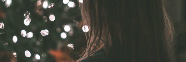 photo of woman standing in front of christmas tree out of focus