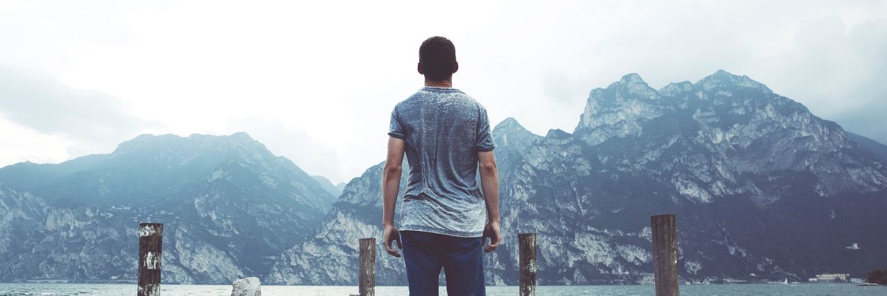 How I Defined 'Laziness' and How I'm Embracing It With OCD back fo man in shorts and a t shirt walking on a rocky dock overlooking the mountains