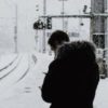photo of man in snow by railroad tracks, looking down