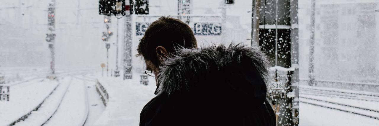 photo of man in snow by railroad tracks, looking down