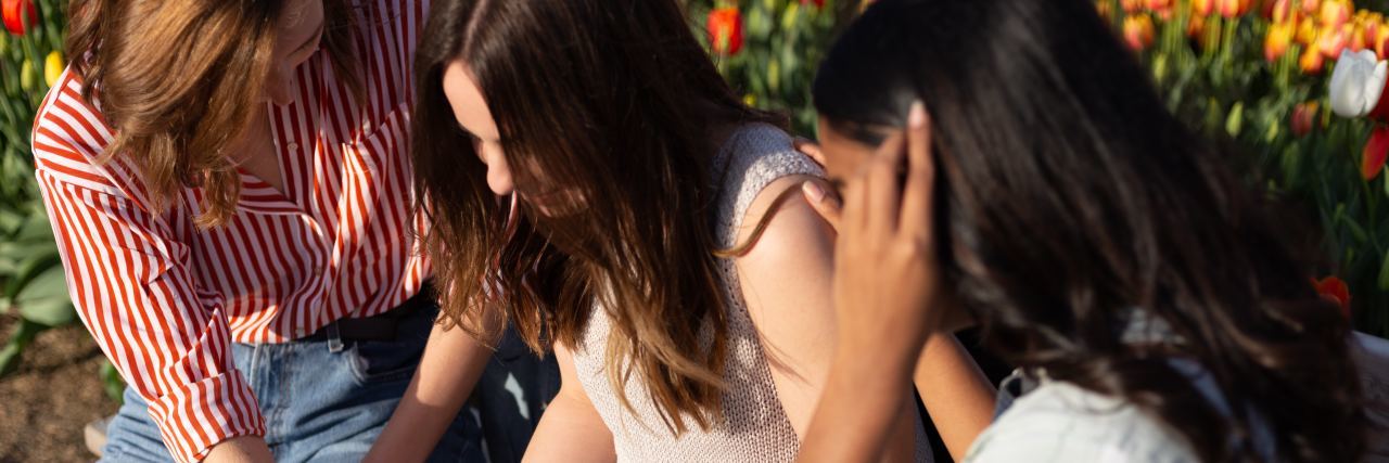 How to Create a Positive Support Network for Mental Illness photo of three women comforting each other sitting down in golden sunlight