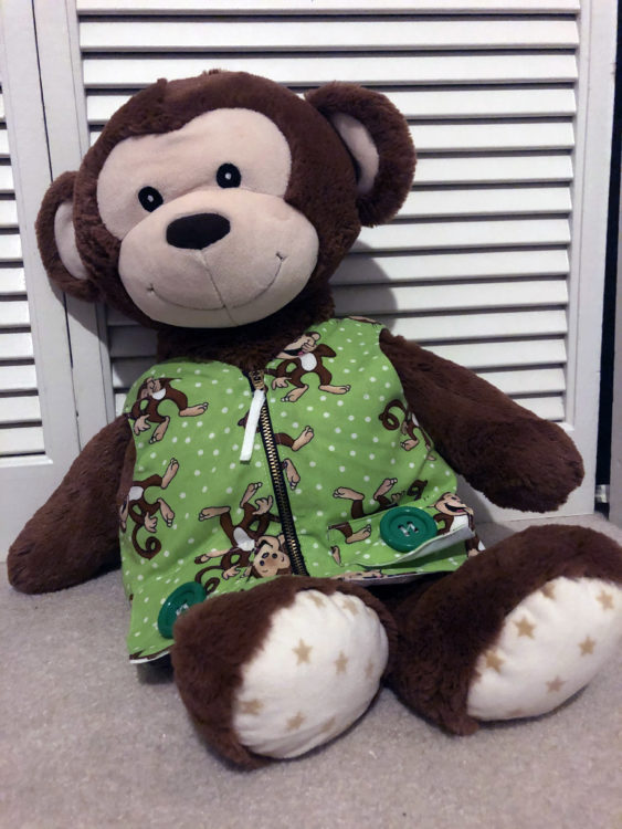 A picture of a big stuffed monkey wearing a green vest.