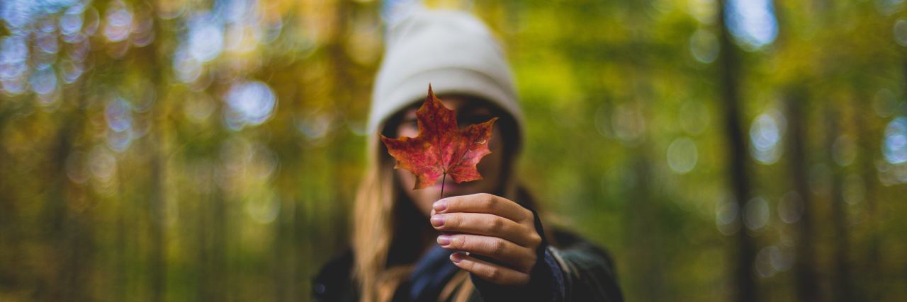 Long Waiting Lists for Mental Health Services in Canadian Maritimes woman in a white beanie holding a red flower in front of her face