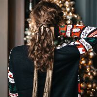 photo of woman with back to camera and hand in hair in front of christmas tree
