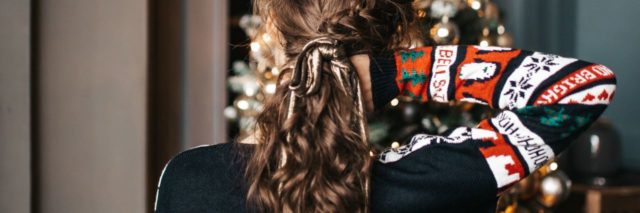 photo of woman with back to camera and hand in hair in front of christmas tree