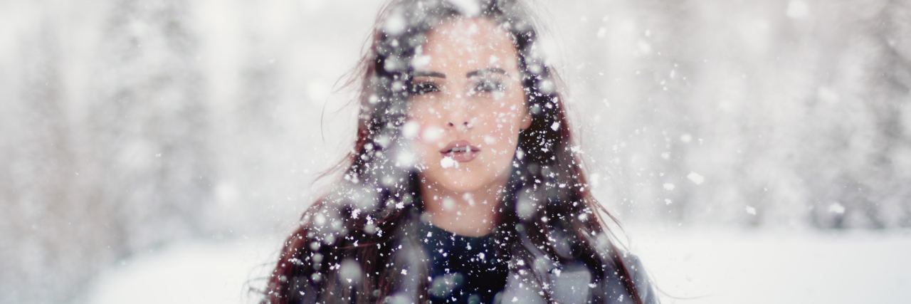 What to Know About Family With Mental Illness During the Holidays photo of young woman standing in heavy snow looking into camera