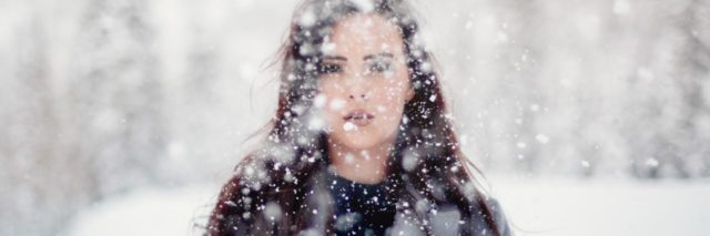 photo of young woman standing in heavy snow looking into camera