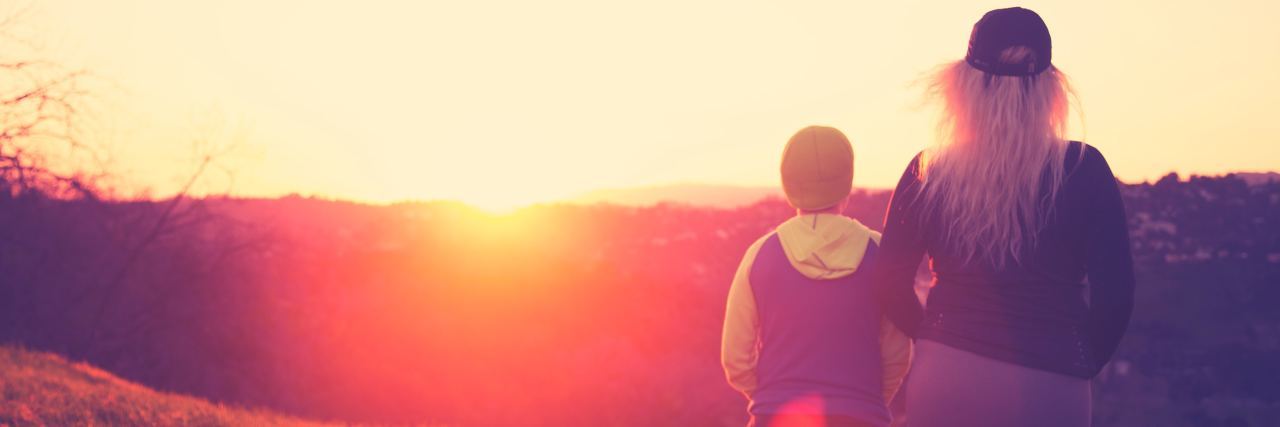 Now That I’m an Adult I Understand the Impact of Family woman and boy standing on field watching sunset
