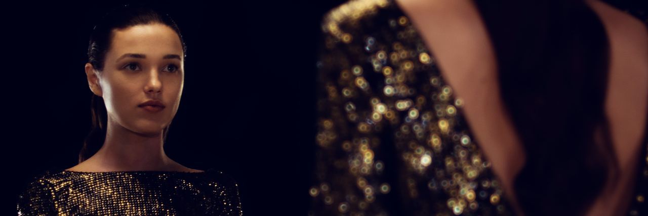 How to Work Through Anxiety and Self-Doubt photo of woman in sparkle dress looking into mirror sitting crosslegged on floor