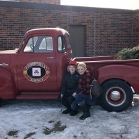 Christina with her son Urijah posing by an antique pickup truck.
