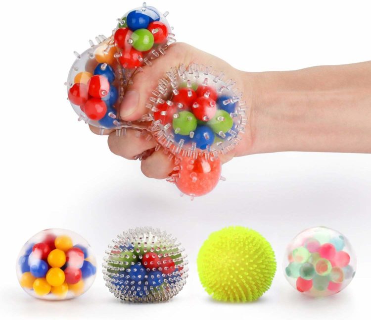 four stress balls and one hand squeezing a colorful stress ball above the other ones