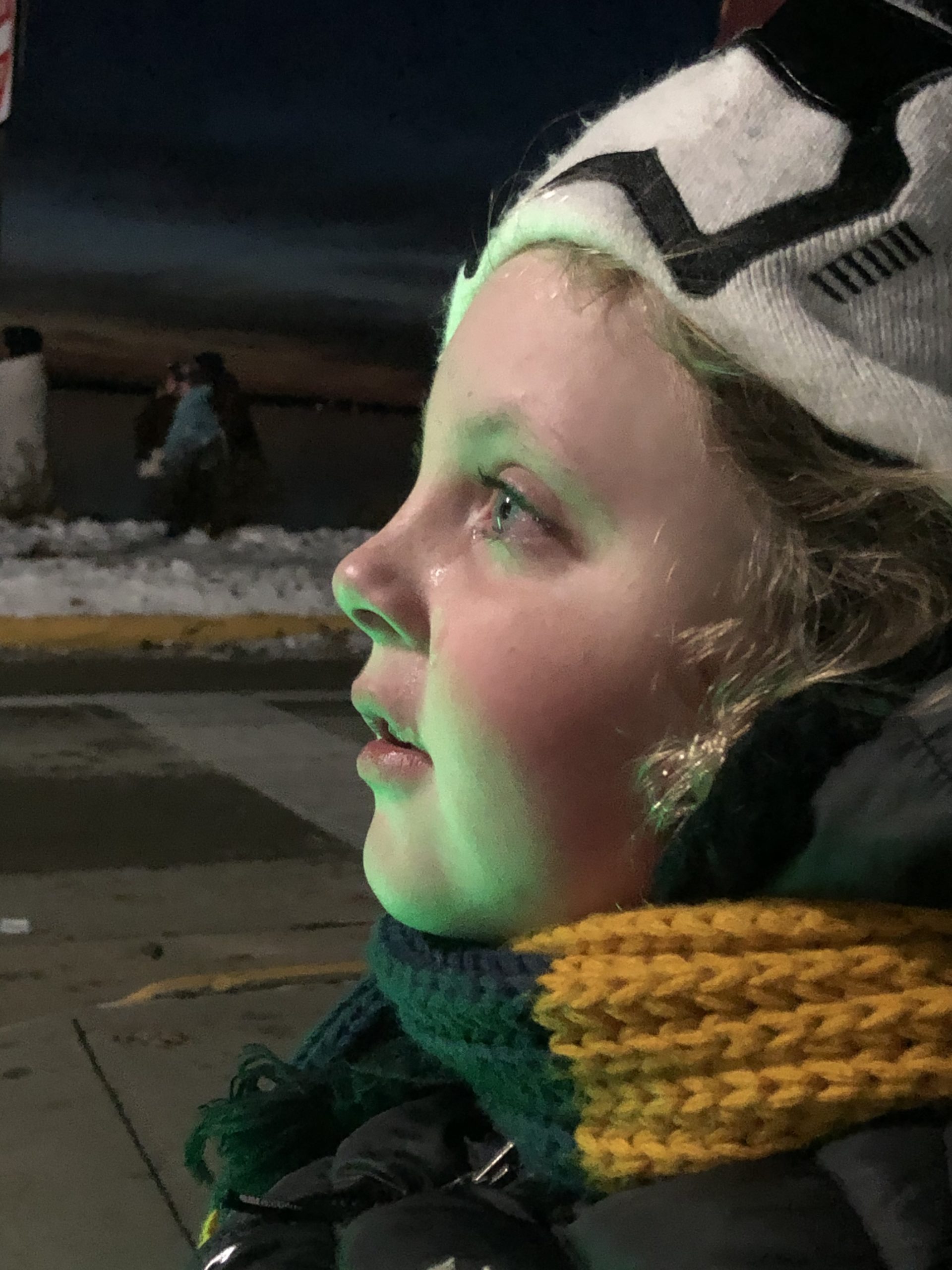 Urijah watching the sky, his face lit by a green firework.