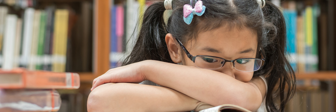 Living With ADHD: Difference Between Childhood, Adolescent, Adult ADHD student in library laying on book
