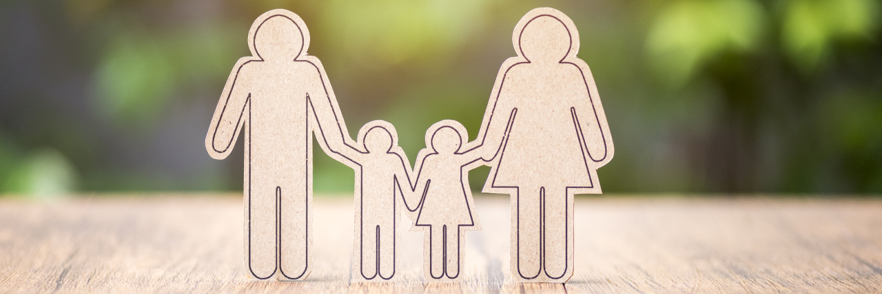 The Truth Behind the ‘Perfect’ Family Photo I Posted on Social Media A paper cut out of a mom, a dad and their two kids.