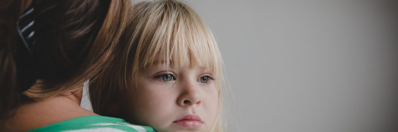 blonde little girl crying, back of the mother holding her