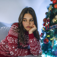 Lonely women sitting on the the sofa at home during christmas.