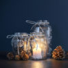Mason jars with candles and decorative pine cones.