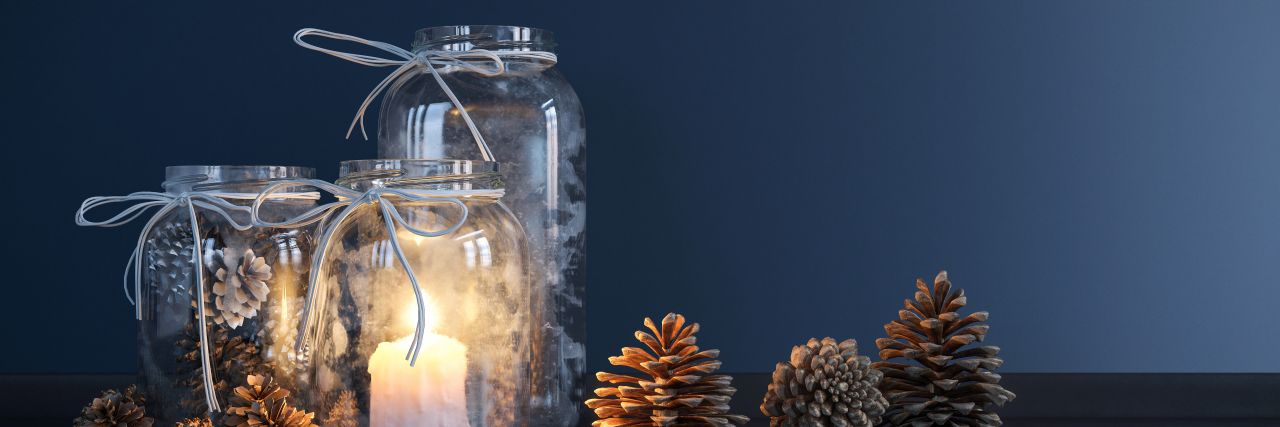 Mason jars with candles and decorative pine cones.