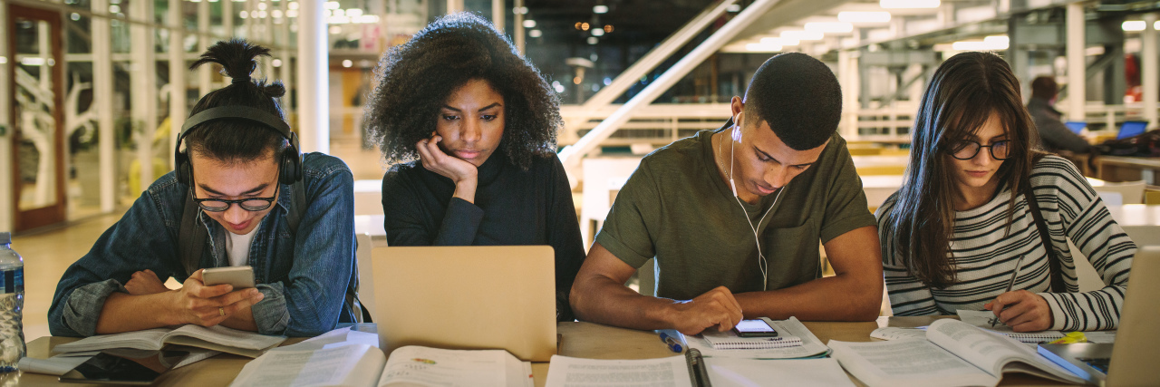 Tips for Attending College With a Chronic Illness Multi-ethnic students sitting at college library.