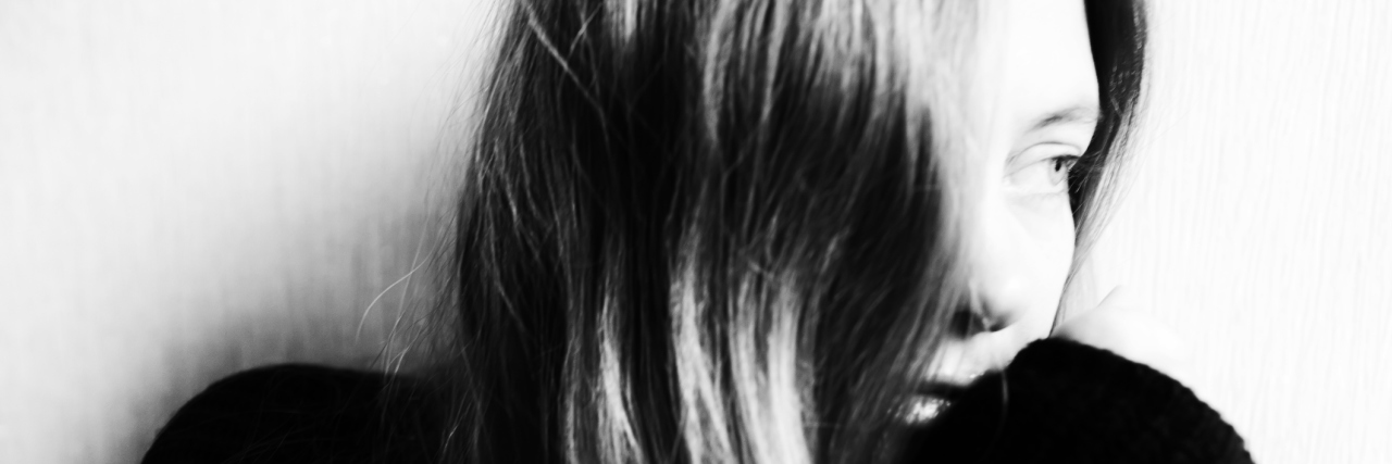 Using the Right Terminology to Address Mental Illness A woman sits alone solemnly looking off to the side.