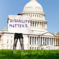 Protester holding sign reading "Disability Matters."