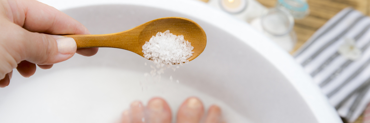 Adding Epsom salt to foot bath water.