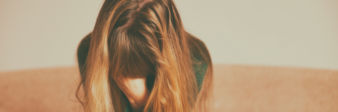 Medication for My Depression and Anxiety Made Me Feel Terrible First woman with blonde hair sitting on the couch with her head in her hand holding a handful of pills