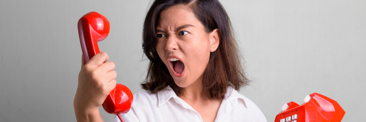 Woman yelling at the phone receiver.