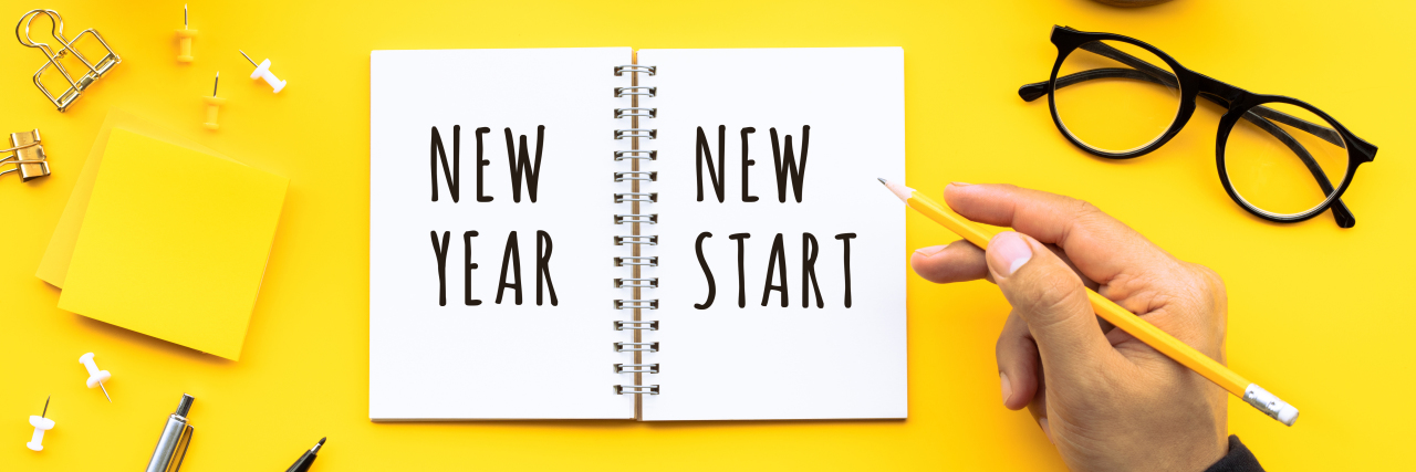 Lessons You Learn in the New Year After Living With Illness New year new start text with youngman writing on notepad on color desk table.Business goal-plan-action and resolution concepts ideas