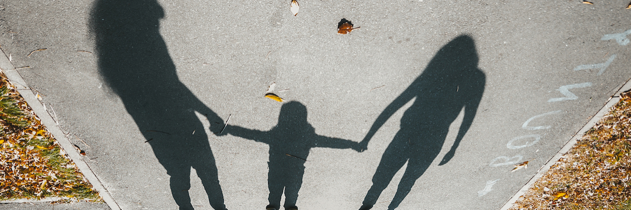 Atlanta Mother Leaves Her Son With Down Syndrome at a Hospital Shadows of a family with little kid on the asphalt road with autumn leaves.