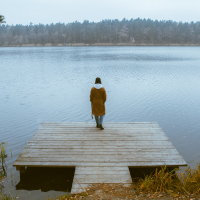 woman standing on a pier near a lake, focus on her back
