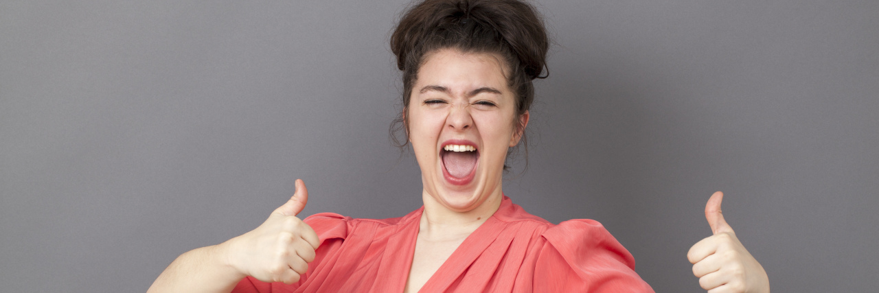 4 Things That I'm Grateful for in 2019 Despite My Chronic Illness woman in a pink dress with hair up winking and smiling at camera with 2 thumbs up