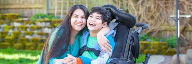 woman hugging a child in a wheelchair and smiling
