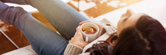 a woman relaxing on a couch holding a cup of tea