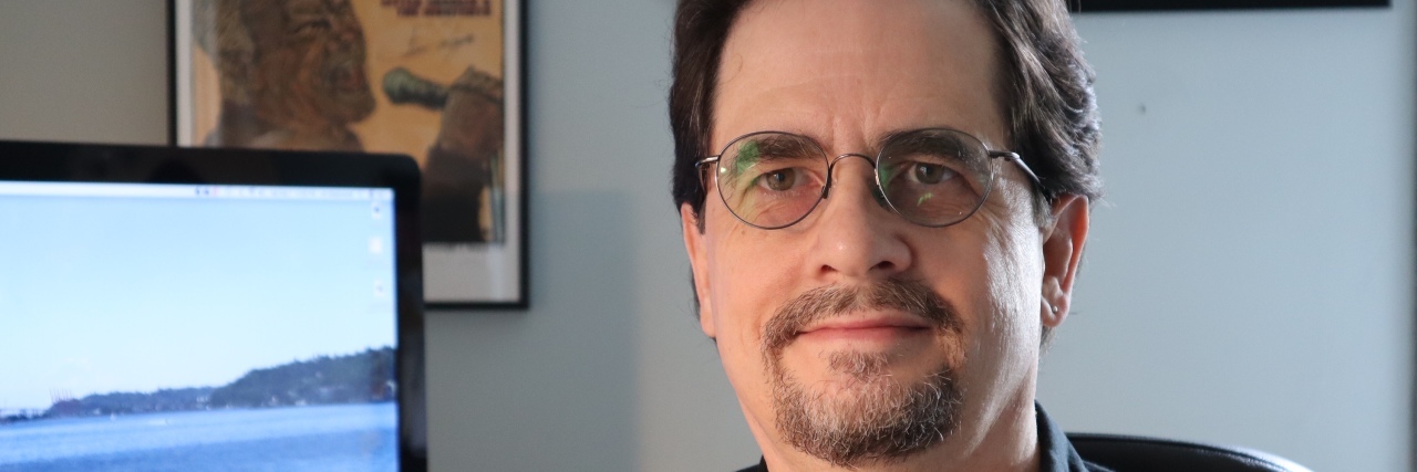 How I Tackled My Panic Disorder by Conquering My Fear of Flying A man sits looking into the camera with a computer in the background.