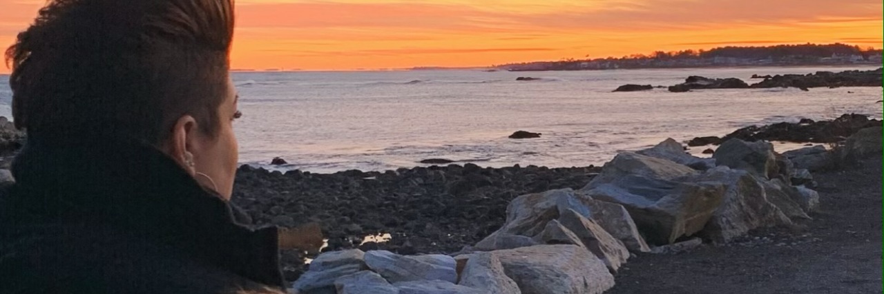 Hearing Hurtful Comments When You Have an Invisible Illness A woman looking at a sunset over the water