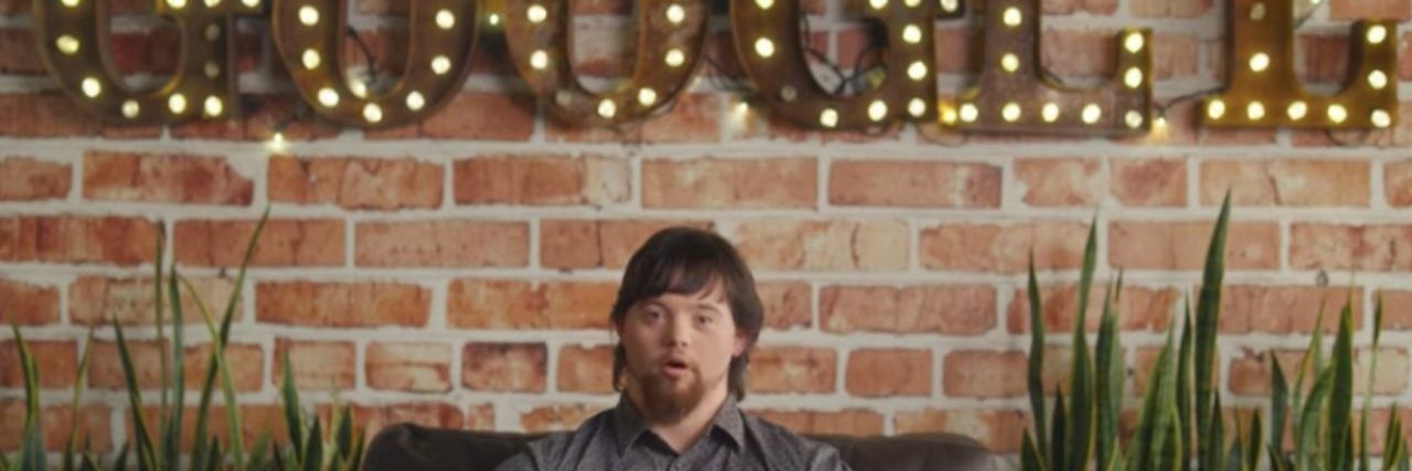 Person with Down syndrome sitting on a couch underneath a Google sign