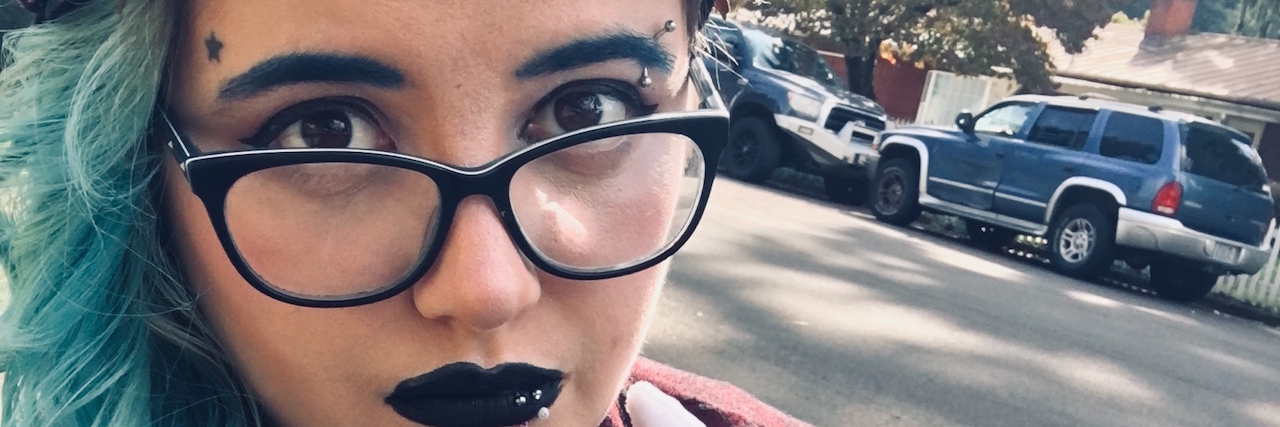 Learning About Self-Love and Body Acceptance Woman wearing glasses with blue hair and looking at the camera