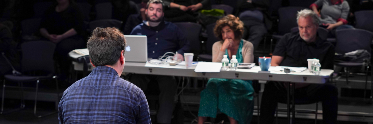 Actor Vincent D'Onofrio sitting with two other industry members evaluating the work of an actor. A man sits before them.