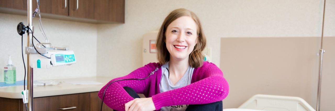 Stopping Full-Time Work Because of Chronic Illness Claire sitting on a bed near an infusion machine in the hospital.