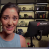 screenshot from peloton exercise bike ad showing woman taking vlog with exercise bike behind her, looking in pain or tired
