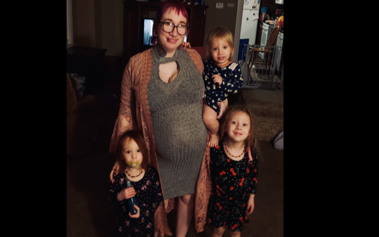 a pregnant mom is standing with her three daughters