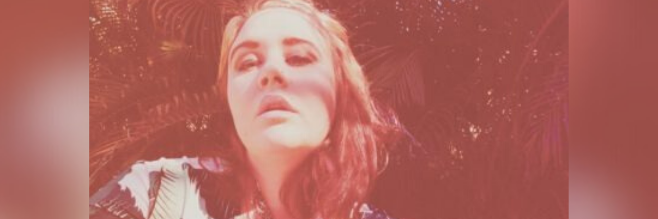 How Taking Selfies Every Day Has Improved My Mental Health selfie author took with a red tint, eyes looking up, and her hand on the side of her head