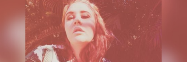selfie author took with a red tint, eyes looking up, and her hand on the side of her head