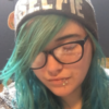 photo of contributor with blue hair, glasses and a hat which says "selfie", with eyes closed