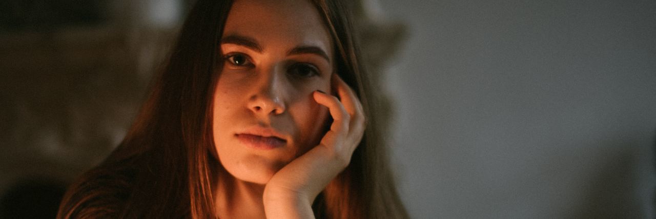 What a Mental Health Recovery Relapse Looks Like photo of woman sitting at table with head resting on hand, illuminated by soft light