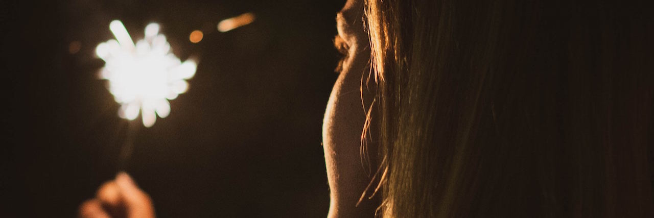 Breaking Down My New Year Resolutions as Someone With Bipolar Disorder Woman holding and looking at a sparkler