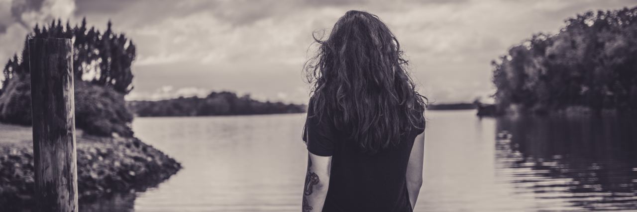 What Is a Major Depressive Episode With Bipolar Disorder sepia tone photo of woman looking out at lake with trees on either side and in the distance