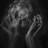 black and white distorted photo of woman screaming with her hands grasping her own face