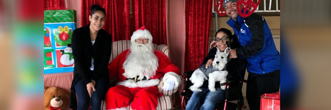 Tylia Flores sits in her wheelchair next to Santa Claus, with other relatives nearby.